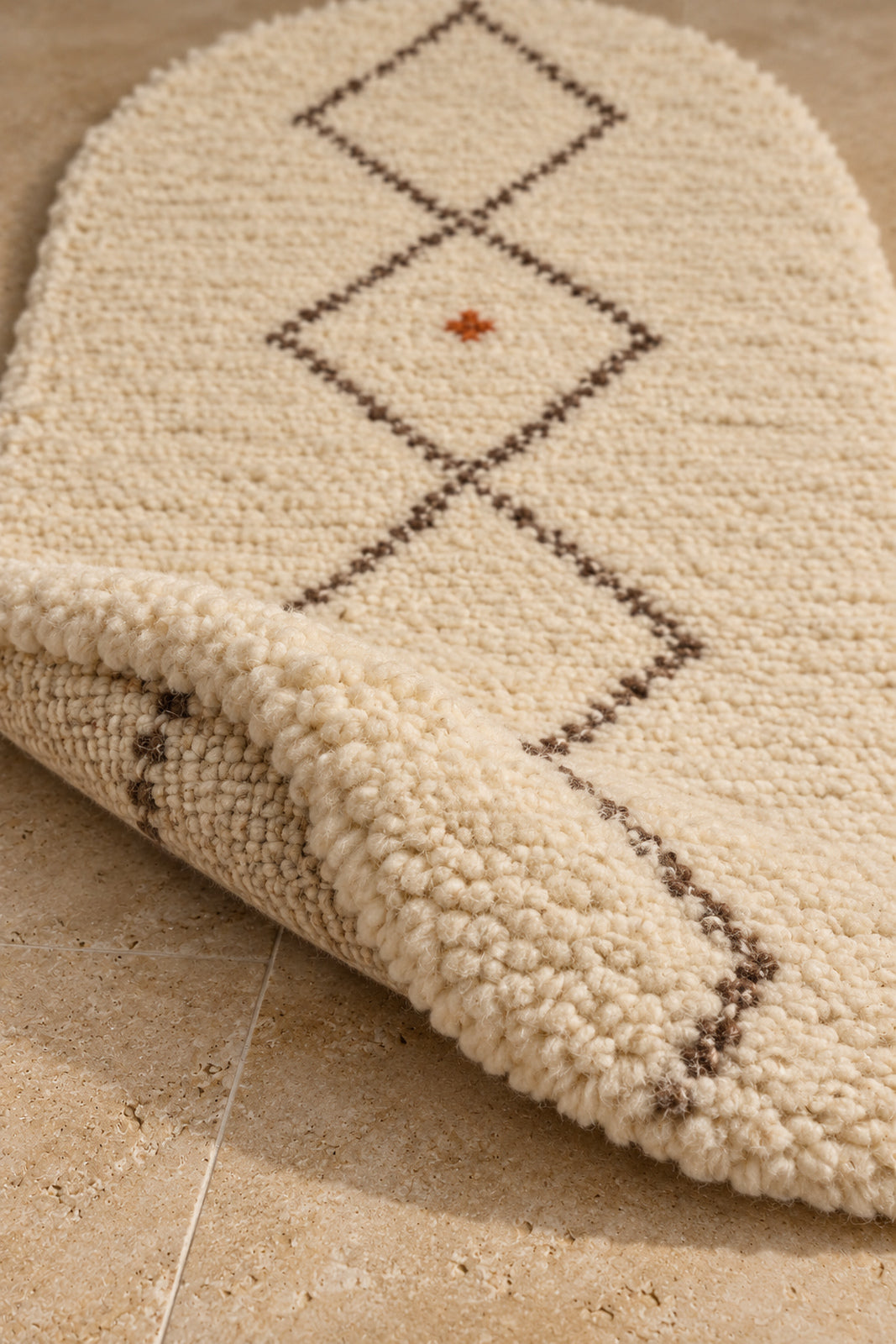 Thick pile of Beni Ourain oval rug model TF-01 on a folded corner