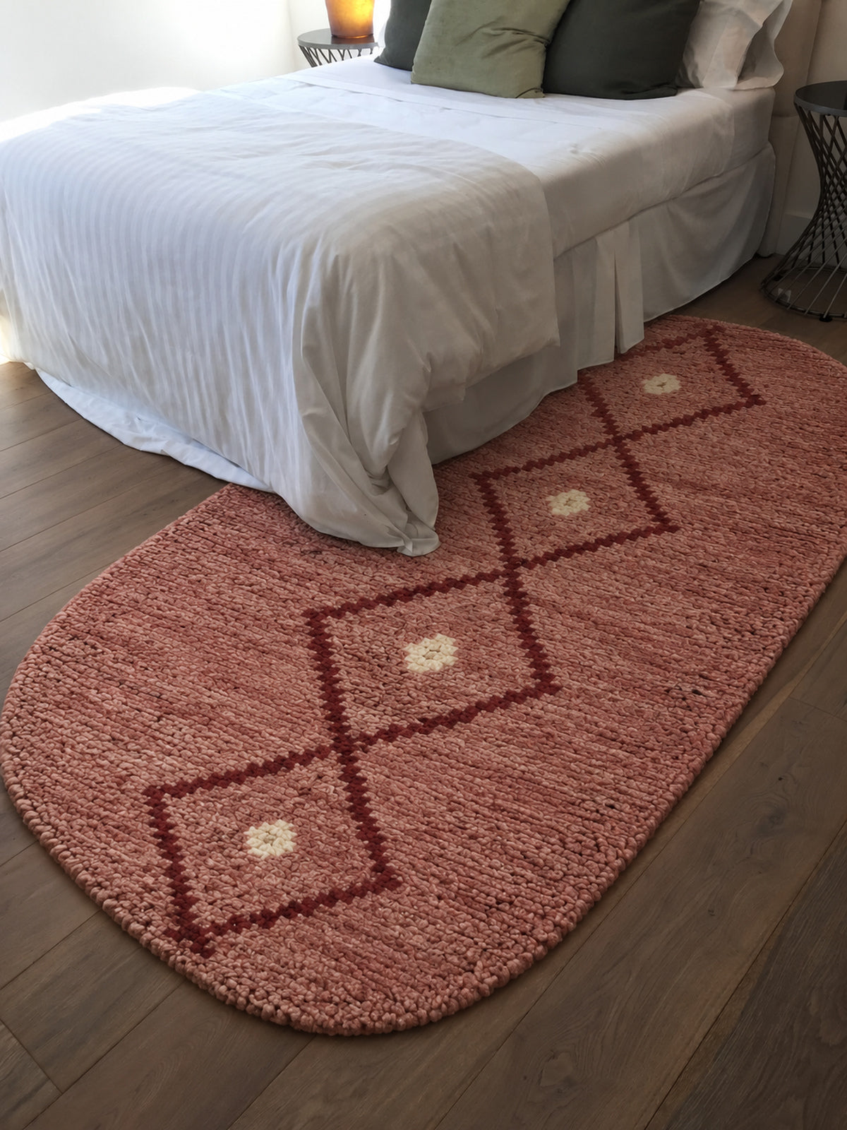 Pink Beni Ourain oval rug with a burgundy diamond chain in a styled interior