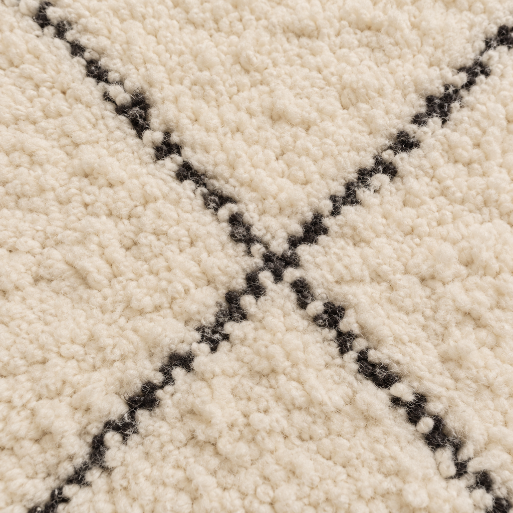 Détail de la texture ivoire et des lignes noires du tapis Beni Ourain