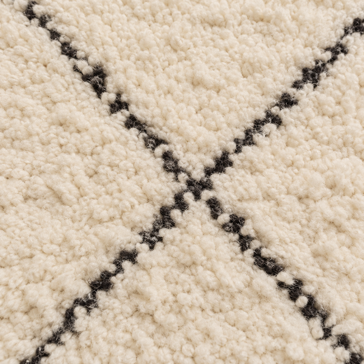 Détail de la texture ivoire et des lignes noires du tapis Beni Ourain